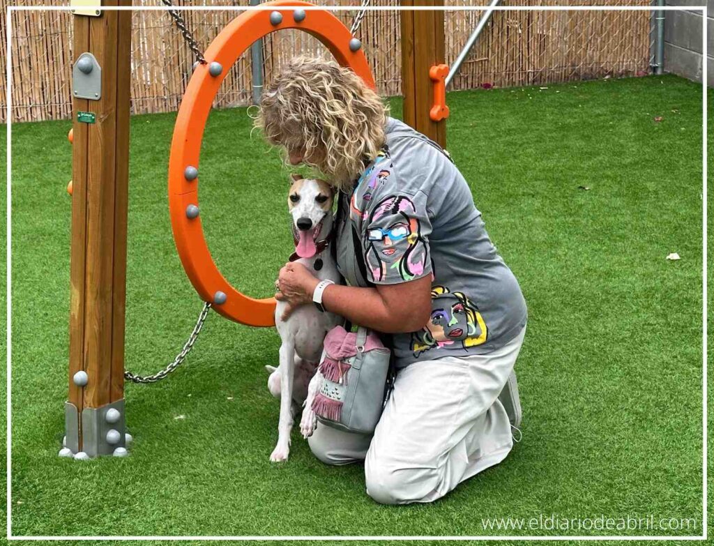Irene sonríe mientras posa con su Whippet, Abril, en el centro del pipicán de Verdecora, mostrando el vínculo especial que tienen en este espacio diseñado para perros.